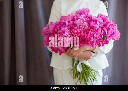 Hände einer Frau mit rosa Pfingstrosen Blumenstrauß Stockfoto