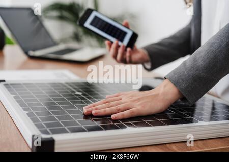 Geschäftsfrau lädt Mobiltelefon mit tragbarem Solarmodul, Nahaufnahme Stockfoto