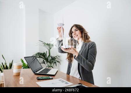 Junge Ingenieurin, die in einem modernen Büro mit Windturbinenmodell arbeitet Stockfoto