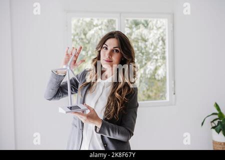 Weibliche Unternehmerin, die im Büro mit Windturbinenmodell steht Stockfoto