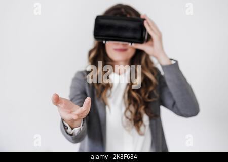 Gestikulierenden jungen Geschäftsfrau mit Virtual-Reality-Simulator im Büro Stockfoto