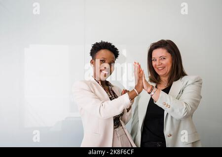 Glückliche Geschäftskollegen, die sich vor einer weißen Wand fünf Punkte geben Stockfoto