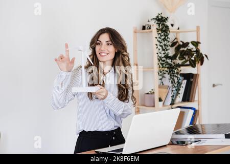 Junger Unternehmer mit Windturbinenmodell in nachhaltigem Büro Stockfoto