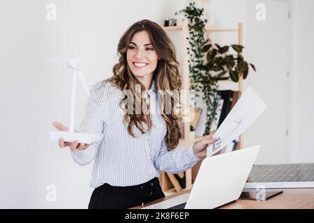 Junger Unternehmer mit Windturbinenmodell in nachhaltigem Büro Stockfoto