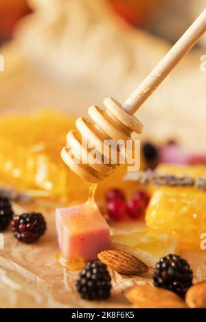 Mandeln, Brombeeren, Käse und Honig tropfen aus dem Honigtauchmittel Stockfoto