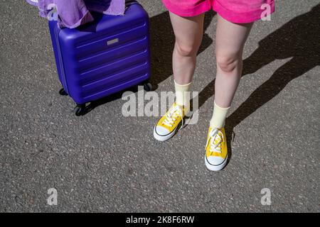 Frau in Leinenschuhen, die mit Gepäck auf der Straße steht Stockfoto