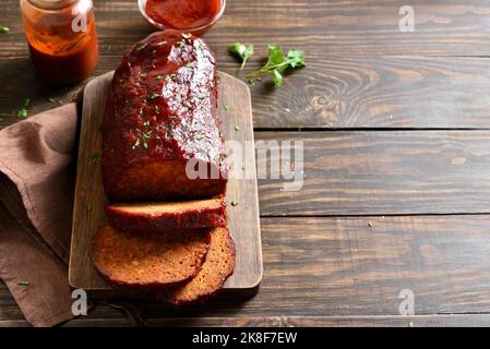 Hackbraten mit Glasur auf Schneidebrett auf Holzhintergrund mit freiem Textraum. Stockfoto