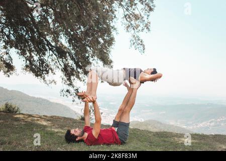 Junges Paar, das Yoga auf der Bergspitze praktiziert Stockfoto