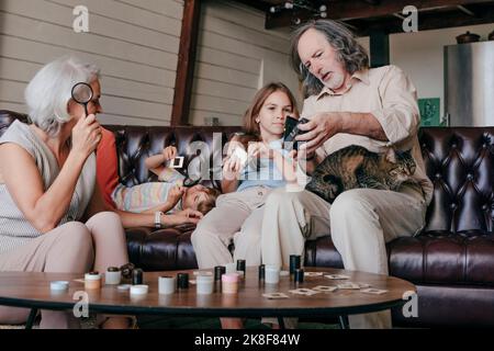 Großeltern stellen zu Hause der Enkelin eine alte Filmkamera und Filmdias vor Stockfoto