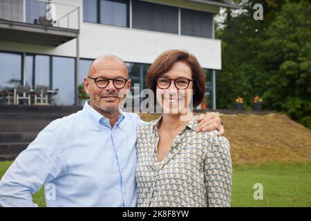 Liebevolles Seniorenpaar, das vor dem Haus steht Stockfoto