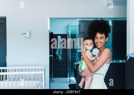 Fröhliche Frau mit Baby zu Hause Stockfoto