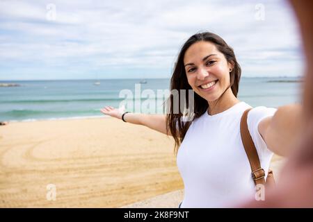 Glückliche Frau, die am Strand Selfie macht Stockfoto