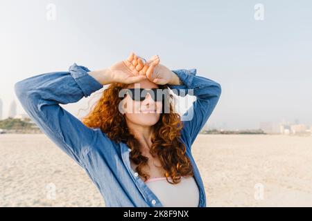 Lächelnde Frau mit Sonnenbrille am Strand Stockfoto