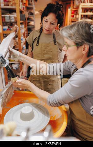 Töpfer arbeiten zusammen am Töpferrad in der Keramikwerkstatt Stockfoto