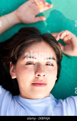 Junge Frau, die auf dem Sportplatz liegt Stockfoto