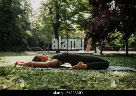 Fitnesstrainer macht Yoga im Park Stockfoto
