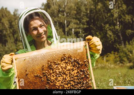 Lächelnder Imker hält Bienenstock an sonnigen Tagen Stockfoto