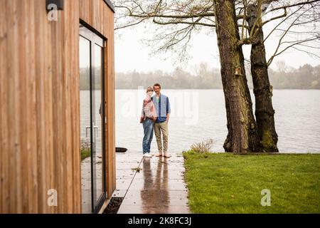 Schwangere, die mit einem Mann auf der Veranda vor dem Haus steht Stockfoto