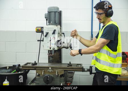 Junger Techniker, der in der Werkstatt mit der Maschine arbeitet Stockfoto