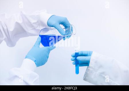 Wissenschaftler gießt blaue Flüssigkeit in das Reagenzglas im Labor Stockfoto