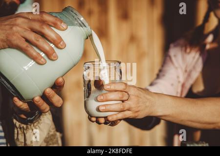 Mann, der an sonnigen Tagen frische Milch in das Glas gießt Stockfoto