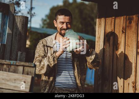 Glücklicher reifer Mann, der an sonnigen Tagen frische Milch aus dem Glas genießt Stockfoto