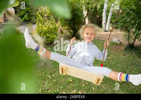 Glückliches Mädchen schwingt auf Schaukel im Garten Stockfoto