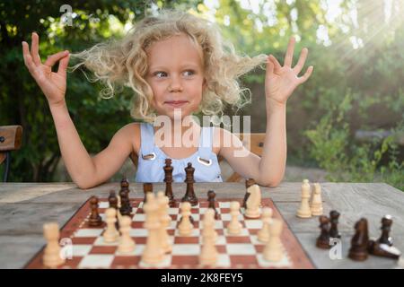 Nettes Mädchen, das mit Haaren vor dem Schachbrett sitzt Stockfoto