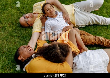 Glückliche Frau mit Mann und Kindern liegen auf Gras Stockfoto