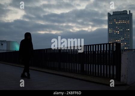 Mann auf der Straße in der Stadt am Abend. Junger Mann in schwarzer Jacke. Studenten spazieren durch die Stadt. Stockfoto