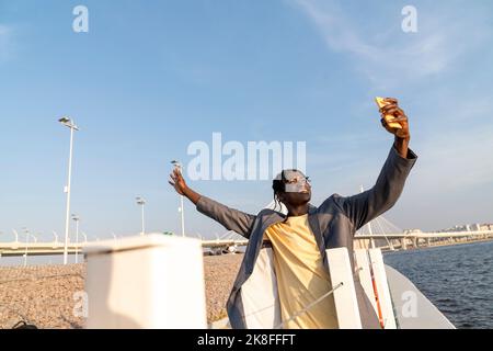 Glücklicher Geschäftsmann, der Selfie über das Mobiltelefon nimmt, das an der Geländer steht Stockfoto