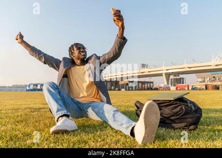 Glücklicher Geschäftsmann, der beim Sonnenuntergang Selfie auf dem Gras macht Stockfoto