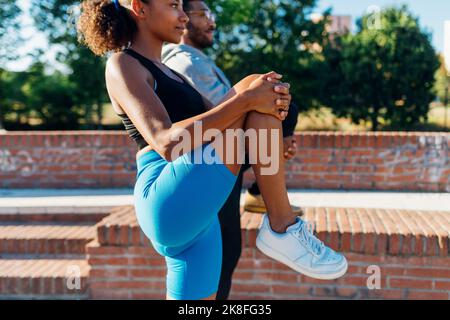 Athleten, die sich an sonnigen Tagen die Beine strecken Stockfoto