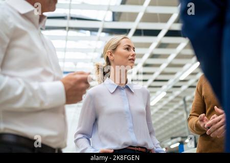 Blonde Geschäftsfrau diskutiert mit Kollegen Stockfoto
