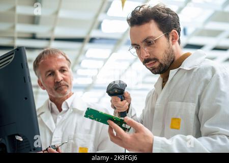 Techniker beim Scannen von Leiterplatten mit Barcode-Scanner in der Industrie Stockfoto