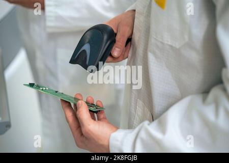 Techniker scannt Leiterplatte mit Barcode-Scanner Stockfoto
