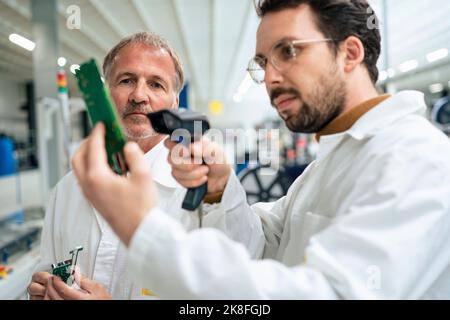 Techniker, die Leiterplatten mit Barcode-Scanner in der Industrie scannen Stockfoto