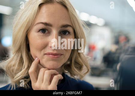 Blonde Geschäftsfrau mit Hand am Kinn Stockfoto