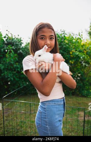 Mädchen hält Kaninchen im Hinterhof Stockfoto