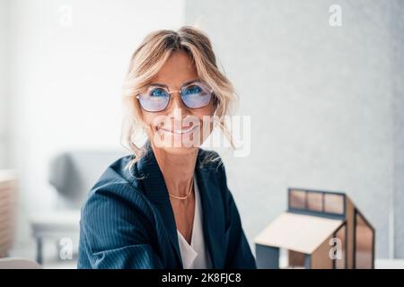 Lächelnder Immobilienmakler mit Brille im Büro Stockfoto