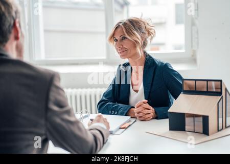 Immobilienmakler mit Händen verflochten Blick auf den Kunden im Büro Stockfoto