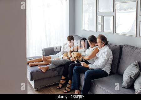 Familie mit Hund auf dem Sofa im Wohnzimmer zu Hause Stockfoto