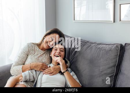 Mutter und Tochter lachen auf dem Sofa im Wohnzimmer zu Hause Stockfoto