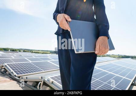 Hände einer Geschäftsfrau, die einen Laptop vor Solarzellen hält Stockfoto