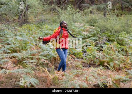 Fröhliche junge Frau, die inmitten von Pflanzen im Wald genießt Stockfoto