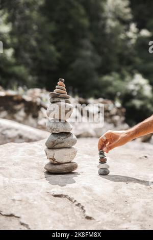 Hand des Mannes, der Steine auf Felsen stapelt Stockfoto