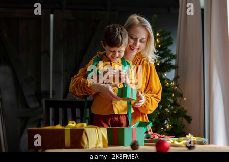 Junge hilft Mutter beim Verpacken von Weihnachtsgeschenken zu Hause Stockfoto