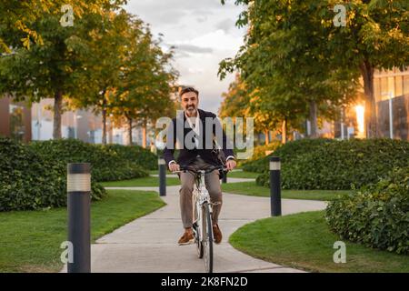 Happy Pendler Fahrrad fahren auf dem Fußweg im Park Stockfoto