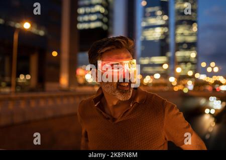 Aufgeregter Geschäftsmann in einer schicken Brille in der Stadt in der Nacht Stockfoto