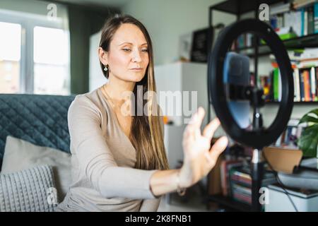 Influencer, der sich selbst zu Hause im Klingellicht auf dem Smartphone aufzeichnete Stockfoto